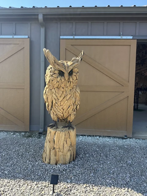Hand-carved wooden owl in front of The Hive barn doors